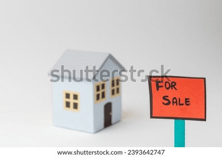 For Sale sign board in front of a sky blue model home, isolated on white background