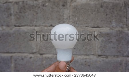 someone holding a white lamp, very simple with a wall background 