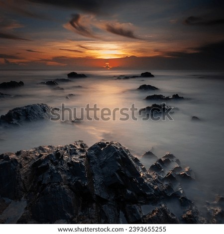 rocky beach with wonderful sunset on square format. Long exposure photography.