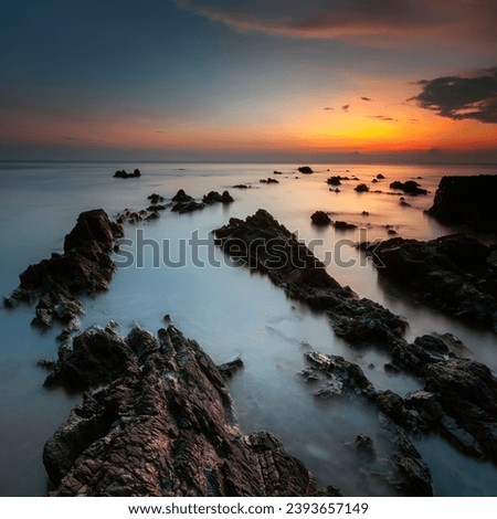 rocky beach with wonderful sunset on square format. Long exposure photography.