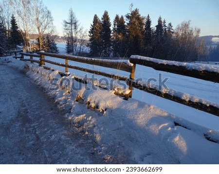 Covered with fresh snow, a wooden fence standing on a mountain road near Glodowski Wierch on a frosty winter morning, Bukowina Tatrzanska, and Poland.