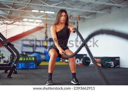 beautiful latin american woman doing battle ropes in the gym Royalty-Free Stock Photo #2393662911