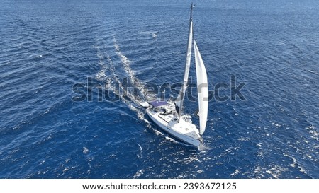 Aerial drone photo of beautiful sail boat with white sails cruising deep Aegean sea, Greece
