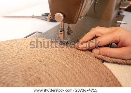 Hand made jute rope placemat at a sewing machine, soft focus close up with motion blur Royalty-Free Stock Photo #2393674915