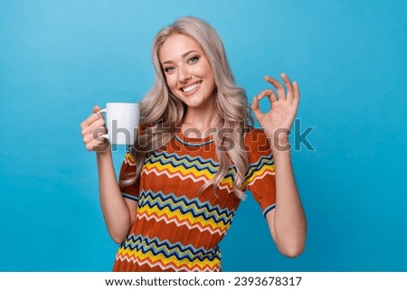 Photo of dreamy sweet girl dressed print shirt drinking cacao showing okey gesture isolated blue color background