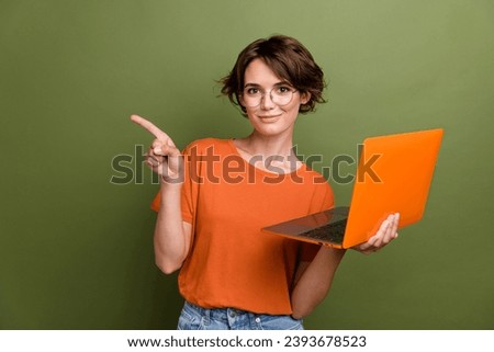 Photo of business woman holding orange case for netbook pointing finger mockup electronics accessories isolated on khaki color background