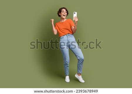 Full size photo of overjoyed satisfied woman wear stylish t-shirt in glasses look at smartphone win bet isolated on khaki color background