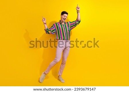 Full length photo of young guy in stylish garment point fingers up enjoying rhythm soundtrack at party isolated on yellow color background