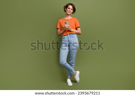 Full size photo of intelligent woman wear stylish t-shirt in glasses hold smartphone write email isolated on khaki color background