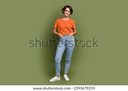 Full size photo of gorgeous satisfied woman wear stylish t-shirt in glasses hold palms in pockets isolated on khaki color background