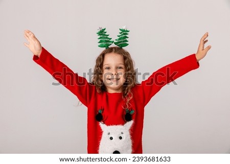 Happy little girl in winter Christmas red sweater smiles cutely and has fun on a white background. Christmas and Happy New Year concept.