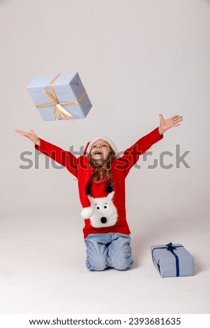 Cute little girl in Santa Claus hat with gifts. White background. Happy New Year and Christmas concept