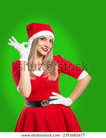 Young santa claus making ok gesture with her hand smiling looking at camera on green background. christmas concept