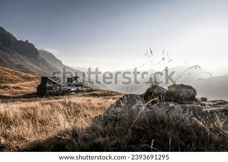 three land rover defender 110 with pop-up roofs staying over night in a grass field - autumn wild life  Royalty-Free Stock Photo #2393691295