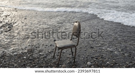old lost rusty chair on pebble beach of Black sea with sunset background.  Batumi, Georgia
