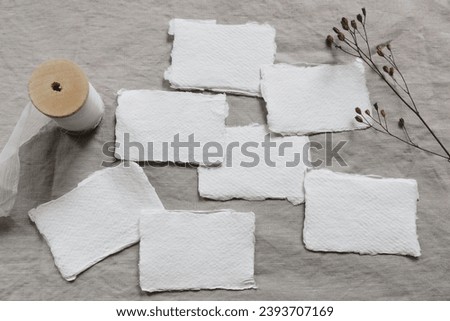 Winter wedding stationery still life concept. Set of blank cotton paper busines, place cards or invitations mockups. Dry flower, seeds on beige linen table cloth background. Sparse flat lay, top view.
