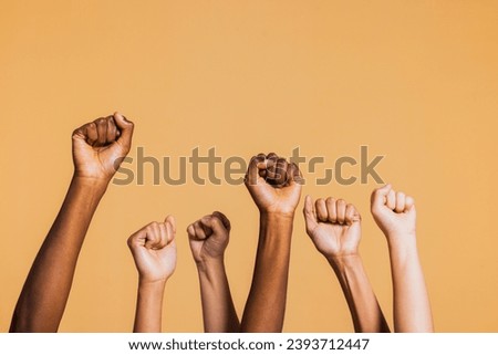 Hands raised with closed fists. Diverse coloured hands raised up with closed fist symbolizing power, determination. Royalty-Free Stock Photo #2393712447