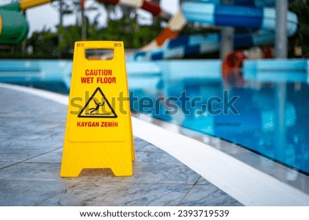 Caution wet floor warning sign near swimming pool in hotel.