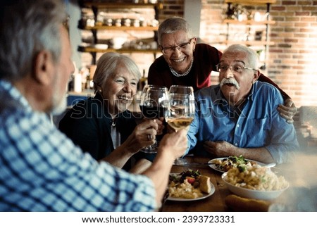 Senior Friends Enjoying a Meal and Wine Together Royalty-Free Stock Photo #2393723331