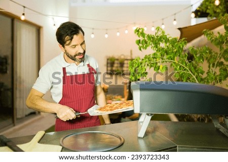 Attractive man cook baking a homemade pizza in the oven ready to eat with his friends for dinner at home