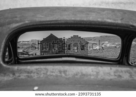 Two old buildings seen through the window of an abandoned car in Bodie Ghost Town.