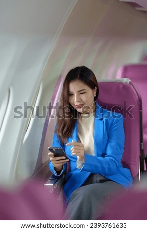Happy Asian businesswoman uses mobile phone to check her meeting schedule during flight. Search information, take photo, check in, online chat. Technology concept, lifestyle.