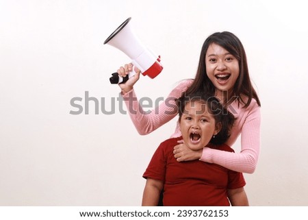 Happy wow excited two young sister shouting using megaphone. Advertisement and Promotional concept. Isolated on white background