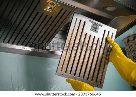 Housekeeping holding a stained filters of cooker hood before cleaning it. Clean your filters every two to three months, depending on your cooking habits. Royalty-Free Stock Photo #2393766645
