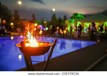 Flaming torch at sunset by the pool Royalty-Free Stock Photo #239378536