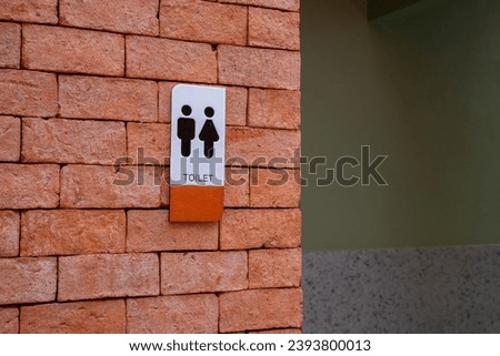Public Restroom Sign signing on Orange Brick Wall Background Toilet Bathroom Signage Plate.