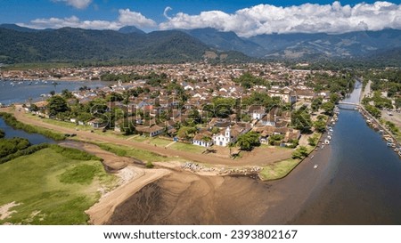 Aerial view to historic town Paraty with tidal river and green mountains in background, sunny sky wi