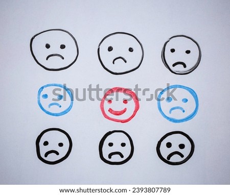Concept for a positive attitude with hand drawn multiple faces on white board background and one that stands out with a smile. Royalty-Free Stock Photo #2393807789
