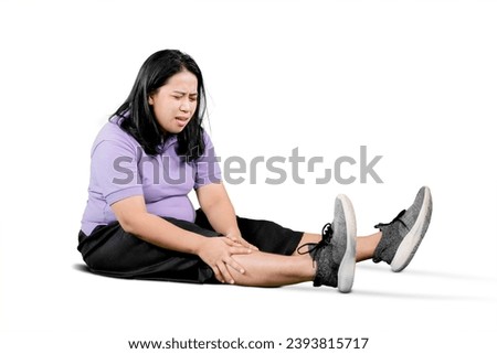 Portrait of young plus size overweight woman holding a knee suffering from osteoarthritis or arthritis against white background Royalty-Free Stock Photo #2393815717