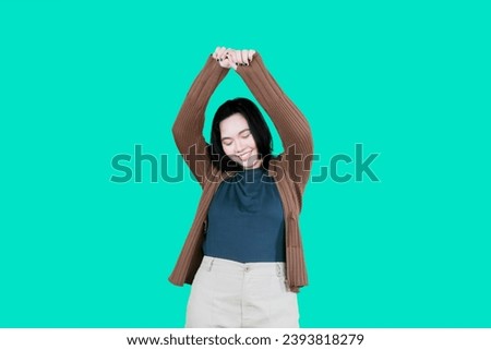 Happy overweight Asian woman enjoying music dancing isolated over green background