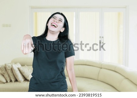 Asian woman laughing out loud hearing funny joke at home