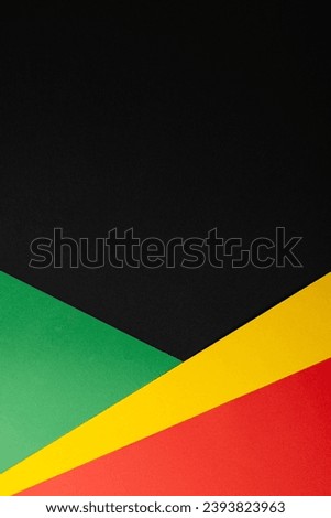 Vertical image of green, yellow and red papers with copy space on black background. Black history month, africa, black culture and history concept.