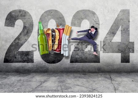 Picture of middle aged man wearing sportswear kicking alcohol, soft drink, cigarettes and junk food over 2024 background - New year resolution