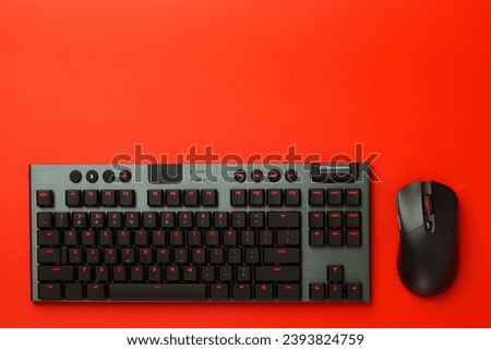 Computer keyboard and mouse on red background close up