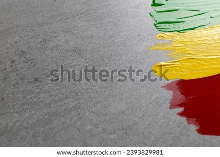 Green, yellow and red paints with copy space on grey stone background. Black history month, africa, black culture and history concept.