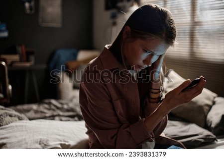 Offended girl with smartphone suffering from night and day cyberbullying Royalty-Free Stock Photo #2393831379