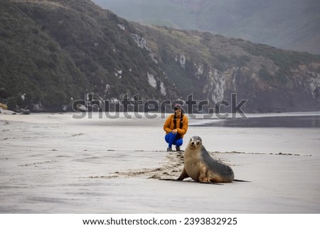 woman and new zealand sea lion posing for a picture together; cute new zealand wildlife spotted in otago peninsula, south island