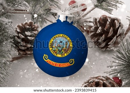 Christmas ball with the flag of Idaho, decorates the snow tree with snowfall. The concept of the Christmas and New Year holiday