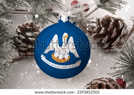 Christmas ball with the flag of Louisiana, decorates the snow tree with snowfall. The concept of the Christmas and New Year holiday Royalty-Free Stock Photo #2393852503