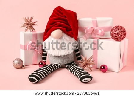 Christmas gnome with gift boxes and balls on pink background