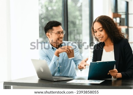 Asian business man and African American woman engaging in business discussion, possibly about merger or joint venture. two companies become one, one of companies often survives while other disappears Royalty-Free Stock Photo #2393858055