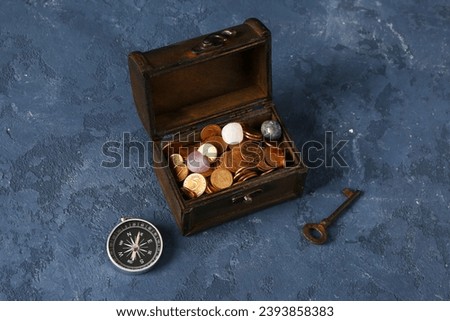 Old chest with treasures, key and compass on grunge blue background