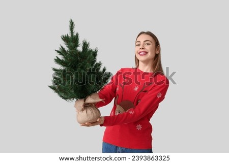 Happy young woman with Christmas tree on white background