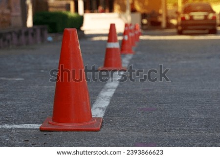 Traffic cones lay on the side of the road. Set up to designate a parking prohibited area along the line because it obstructs the exit. Soft and selective focus.                                
