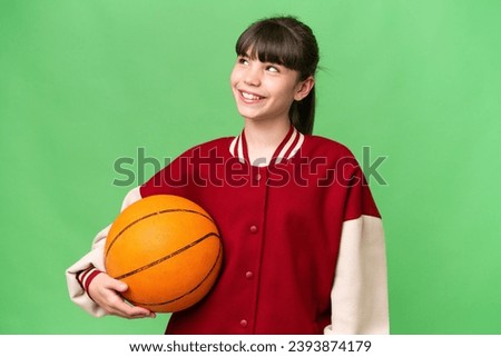 Little caucasian girl playing basketball over isolated background thinking an idea while looking up