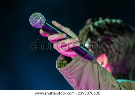 A hand holding microphone on a stage